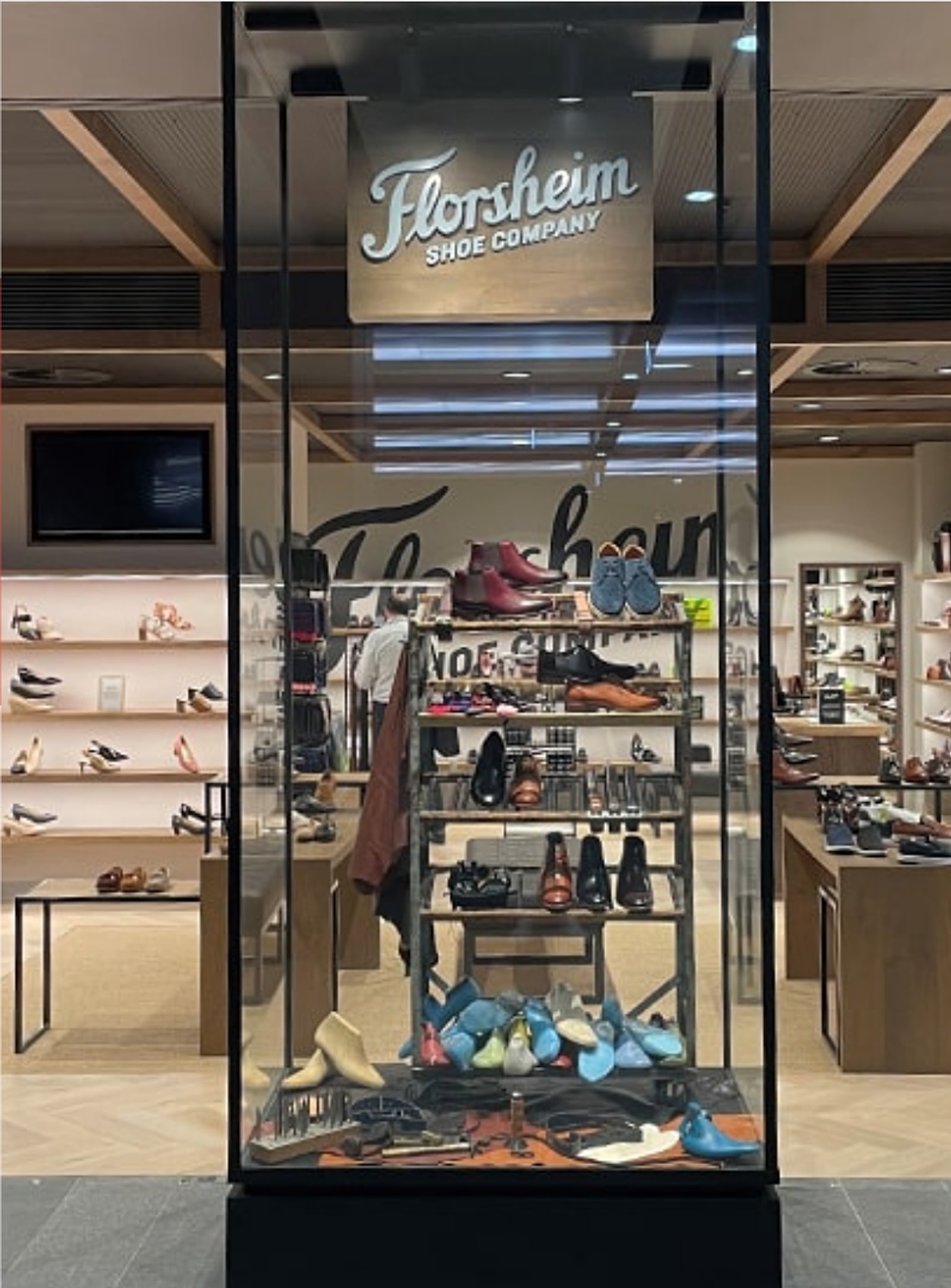 A Florsheim Shoe Company store display case filled with shoes and wooden lasts